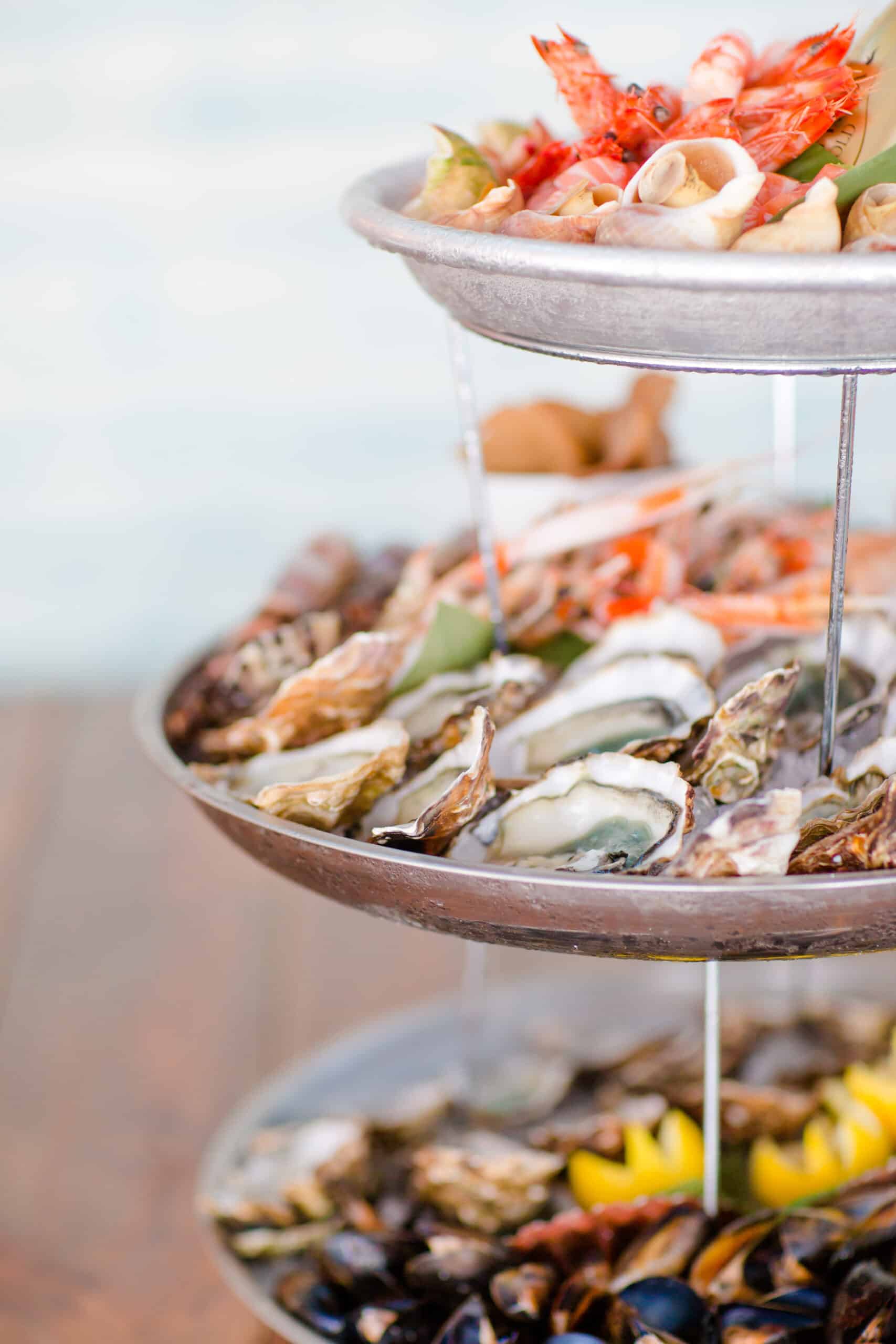 Grand plateau de fruits de mer à trois étages : huîtres fraîches sur glace, crevettes, moules et escargots de mer, garnis de citron.